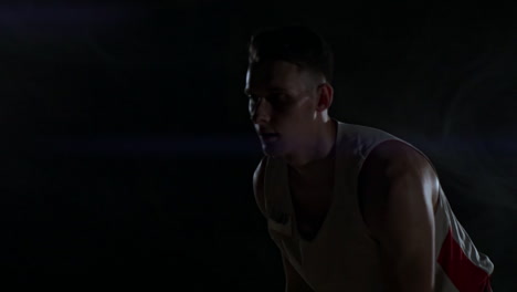 Dribbling-basketball-player-close-up-in-dark-room-in-smoke-close-up-in-slow-motion